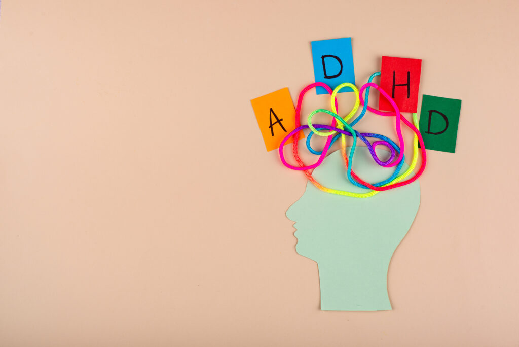 Symboliczna grafika głowy z poplątanymi kolorowymi sznurkami i napisem ADHD, obrazująca chaos myślowy i trudności z koncentracją przy nadpobudliwości psychoruchowej.